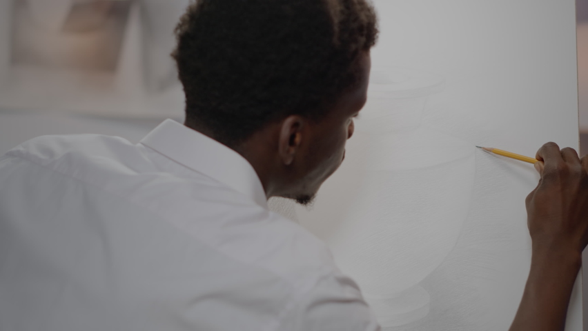 African american artist creating drawing of vase with pencil on white canvas at art studio. Black young adult using craft tools and instruments for innovative project of modern masterpiece