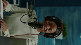 Vertical video: Woman african vlogger recording to camera tutorial about lifestyle in home podcast studio during livestreaming. On-air online production internet broadcast show host streaming live - Powered by Shutterstock - Get 15% off with code: PIKWIZARD15