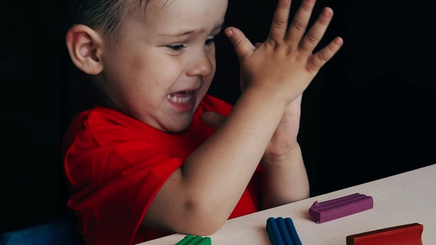 A video in which a small child boy sculpts figures from colored plasticine