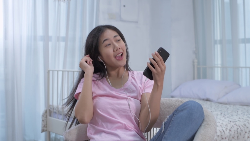 Holiday concept of 4k Resolution. Asian girls are enjoying music in the bedroom.