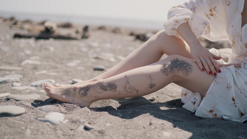Girl with beautiful legs clean her feet from sand