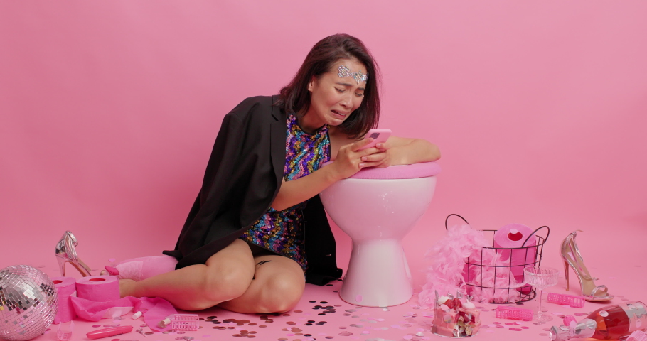 Depressed stressed Asian lady chats with boyfriend has quarrel online sorts out relationships after party tries to make call cries from despair leans on toilet bowl sits on floor in restroom Royalty-Free Stock Footage #1077088493