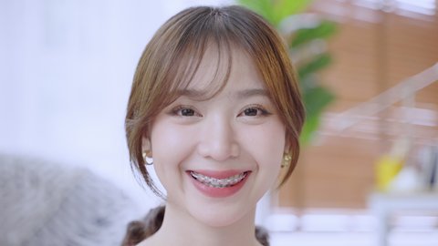 Asian woman with braces smiling until she sees wearing braces, beauty concept
