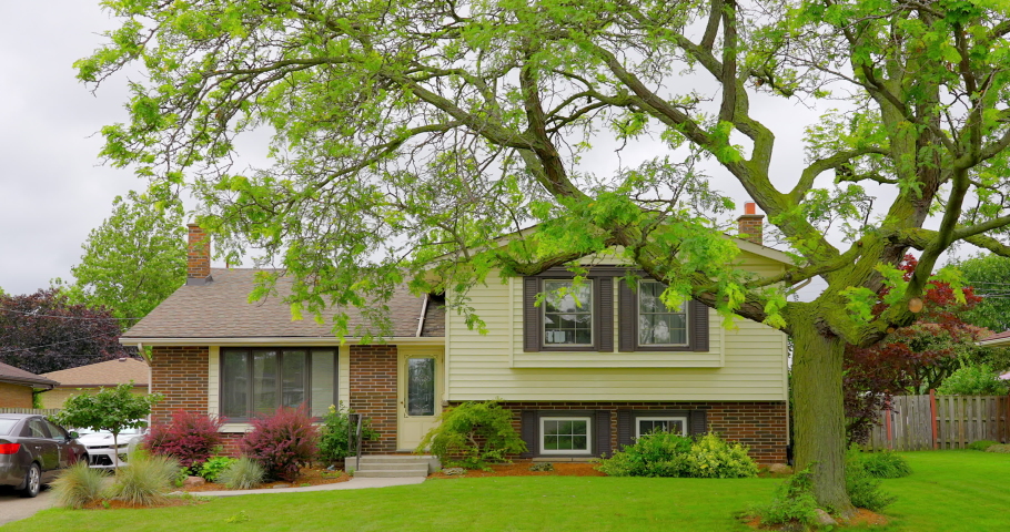 Establishing shot of two story stucco luxury house with garage door, big tree and nice landscape in Toronto, Canada, North America. Day time on July 2021. ProRes 422 HQ.