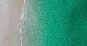 Nature and travel video. Aerial view shot of drone. Top-down view full frame beach sand and water texture and clear. Nature and travel concept. 4K UHD Video clip.