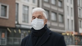 Portrait of old retired businessman, gentleman in coronavirus facemask looks at camera, lockdown restrictions. Mature adult elderly male on city streets. Senior man with graying hair in covid-19 mask. - Powered by Shutterstock - Get 15% off with code: PIKWIZARD15