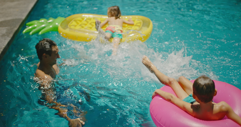 Family playing and splashing in the pool on summer vacation, cinematic family lifestyle