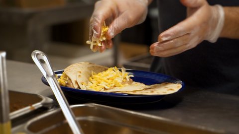Cook prepares bean and cheese tacos in Mexican restaurant kitchen, slow motion HD