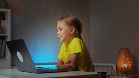 Cute funny kid girl talking to friend, sister, mom or distance teacher during online by video conference call using notebook. Children virtual learning at home concept
