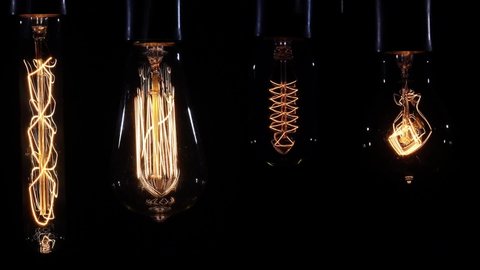 Set of filament lamp with a tungsten spiral pendant lantern lights up and goes out on a black backdrop. Retro styled, vintage light bulb pulsing light in the darkness.