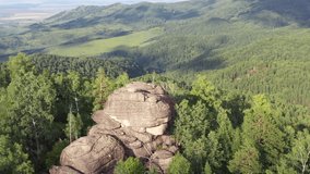 Aerial video of rocks on the top of Kruglaya mountain near the town resort Belokorikha in Altai. Camera rotates around the rock. Russia
