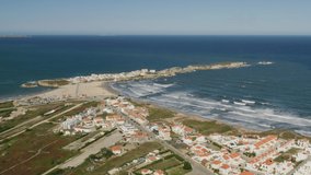 Baleal, Portugal, Europe. Coastline, washed with foamy waves as seen from top. Drone footage of a seaside town with residential block and endemic greenery. High quality 4k footage