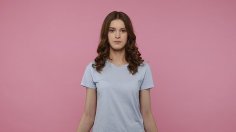Cute female of young age wearing blue T-shirt has fun with red balloons letters, smiling playfully and flirting, demonstrating love, kissing gesture. Indoor studio shot isolated over pink background.