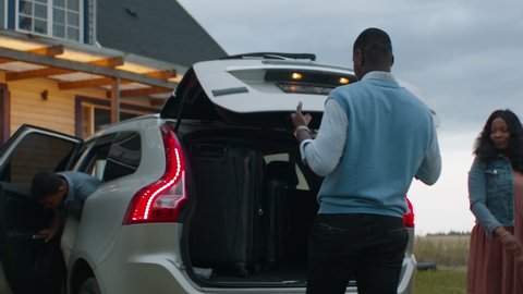   Happy African American family of three arriving by car to their new house. Shot with 2x anamorphic lens