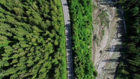 Aerial top view of mountain twisted road and Bus, Van or RV car driving to the mountains. Beautiful summer in the mountains and sunny clean road through green forest.