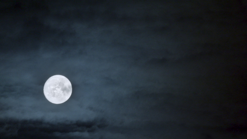Full glowing moon with clouds being blown by winds during storm at nights.