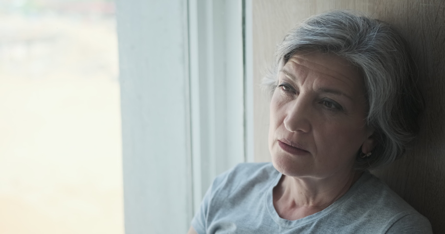 Thoughtful sad worried middle-aged senior woman, thinking of loneliness, sadness, and sorrow. But then she remembers her kids and grandkids and is smiling and feeling happy. Royalty-Free Stock Footage #1077128657