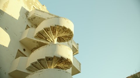 architecture of the southern poor countries. an external spiral staircase attached to the wall of the building. a dilapidated spiral staircase of an unusual house in Africa. travel and architectural