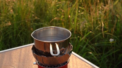 There is steam over a bowl of water standing on a gas stove at the campsite. High quality FullHD footage