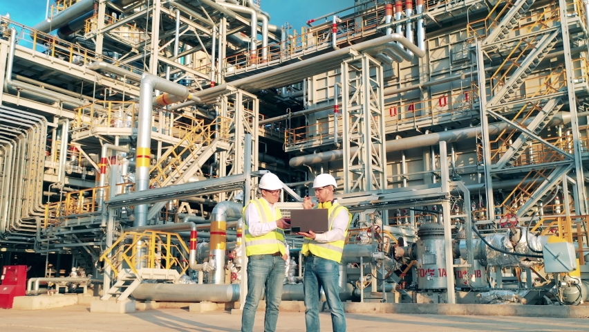 Oil industry, petrochemical factory, refinery concept. Engineers are talking next to the pipes of the oil refinery plant Royalty-Free Stock Footage #1077136037