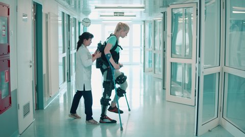 Nurse is helping a female patient to move in the exoskeleton