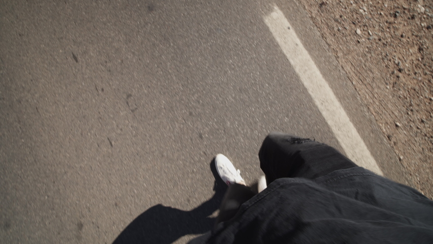 POV footage of male legs walking on road, tilt up and pan reveal of road, car and dry landscape with stones all around. Morocco, Africa