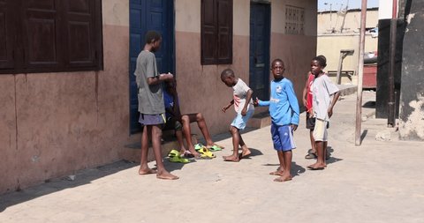 NIMA, GHANA - 20 JUL 2021: Young boys playing dancing schoolyard Accra Ghana. Small poverty centered community. Narrow alleys  foot paths in Muslin area of the city. Concrete and tin.