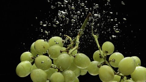 Air bubbles rising from drowning green grapes, close up view