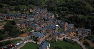 Aerial horizontal 4K footage of a small Spanish village with houses in a green natural environment in the Spanish Pyrenees.