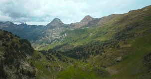 Aerial horizontal 4K footage of huge mountains in a green natural environment in the Spanish Pyrenees.