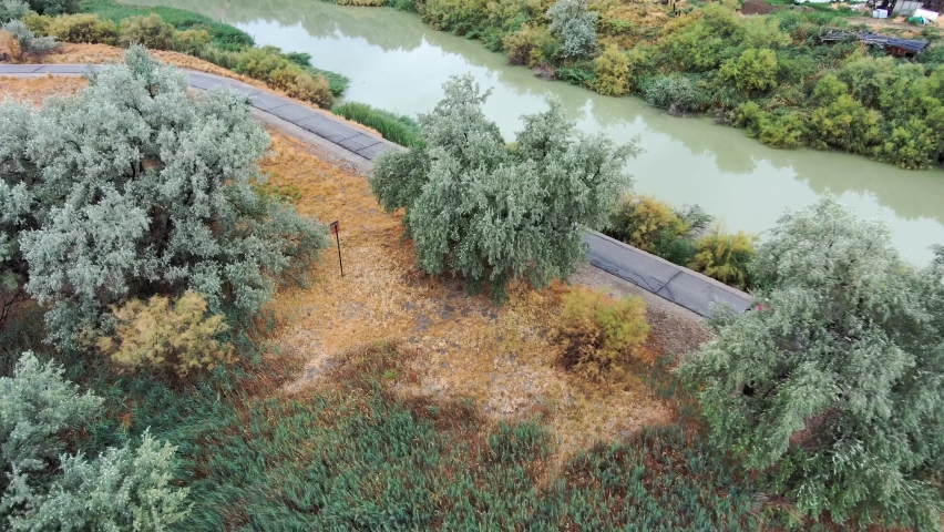 Couple riding bicycles along a trail by a river together - aerial tracking view
