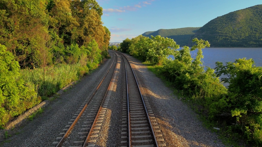 Aerial drone footage of the metro north Hudson Line train tracks during summer next to the Hudson river between beacon and cold spring, new york, usa