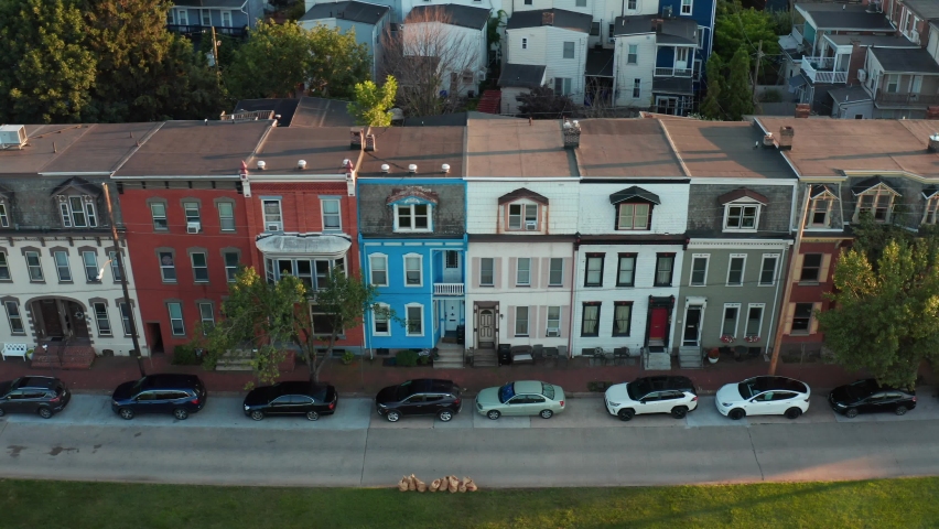 Aerial of rowhomes. Colorful rowhouses, homes, apartments along urban city street in USA. Truck shot at magic hour. Royalty-Free Stock Footage #1077155561