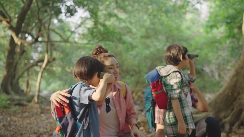 Asian family father and mother parents sash backpack two childhood sons Teach his son to walk, study, learn about nature. Practice using binoculars in the forest park during the holidays Royalty-Free Stock Footage #1077158582