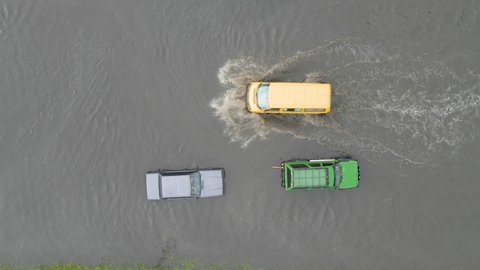 Aerial view of city traffic with cars driving on flooded street after heavy rain. Problems with road drainage system.