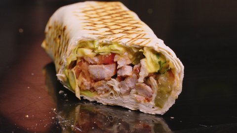 Professional chef is making shawarma at fast food cafe, close-up. He is finishing and wrapping the roll.