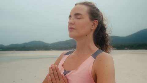 Panoramic Portrait of Calm Healthy succes girl with closed eyes and folded palms stands on the beach in front of the sea
