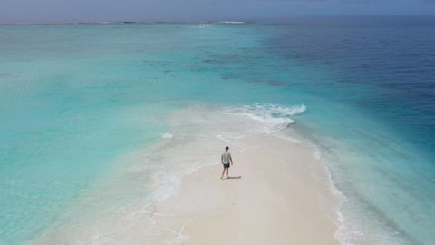 man walking on a beach of tropical island near the ocean