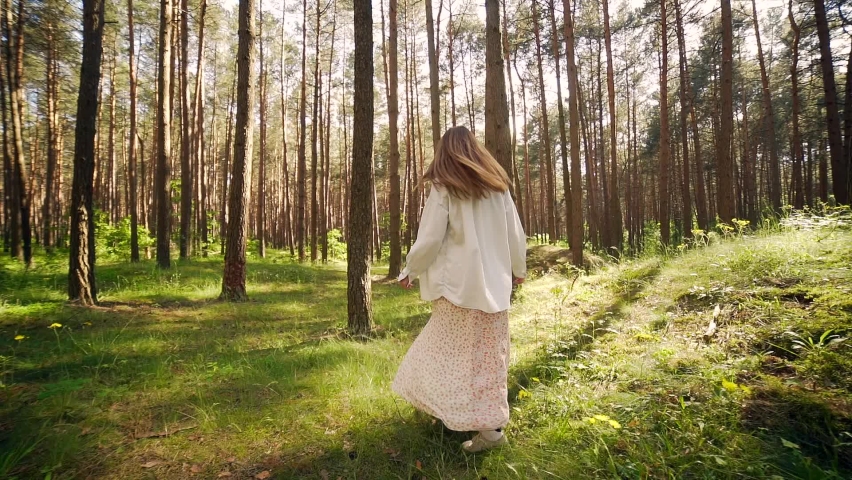 Happy young cheerful woman running away from camera outdoors in pine forest rear view slow motion. Lifestyle Girl walks in park connecting with nature shining in sun at sunset. enjoys life. Happiness Royalty-Free Stock Footage #1077198731