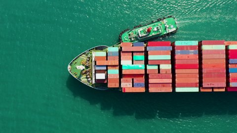 Aerial top view cargo logistics container ship floating in green sea, business and industry service transportation import export international worldwide by shipping containers ocean flight 4k video 
