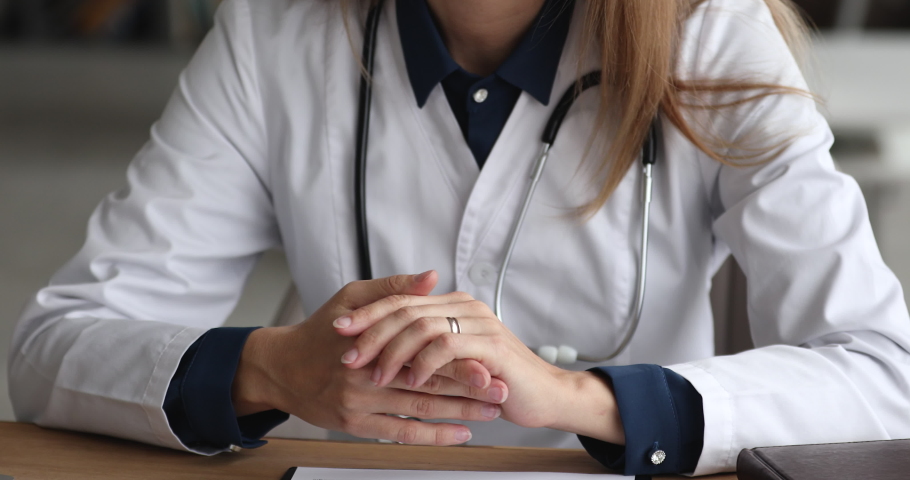 Unrecognizable young female doctor physician general practitioner gesturing, giving professional medical consultation, explaining illness treatment, telling healthcare advice at checkup meeting. Royalty-Free Stock Footage #1077208013