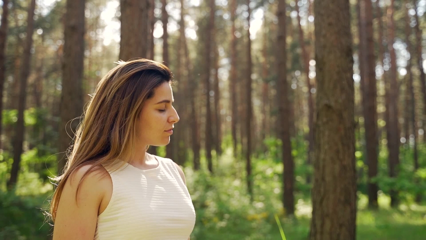 Close-up portrait of a pretty young woman breathes fresh air into her full chest in the middle of pine forest on nature. Outdoor. freshness, peace and quiet. Girl with closed eyes enjoys the sounds Royalty-Free Stock Footage #1077208109