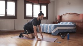 Bearded man using his mobile phone to exercise at home.