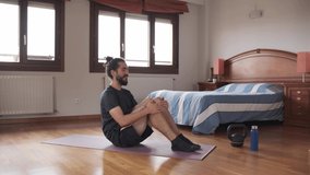 Bearded man doing bicycle crunches at home as part of his daily workout.