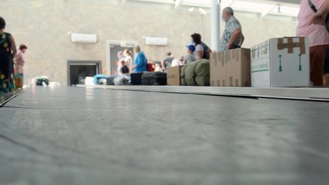 Airport baggage belt. Baggage claim. Bottom view. People in the background are waiting for their luggage. 4k, slow motion