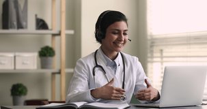 Indian female general practitioner give medical support to patient distantly use video call app, look at computer screen wear headset talk to client makes speech. Remote medicine consultation concept