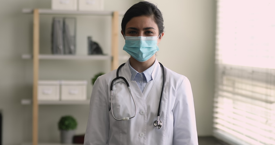 Happy young Indian female doctor in uniform and mask show heart makes love sign with fingers, express care and support for patient. Cardiology, healthcare, check up of cardiovascular diseases concept Royalty-Free Stock Footage #1077231062