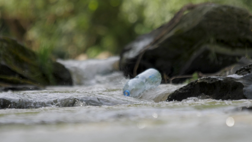 Plastic garbage in nature clean up waste water. Volunteer hands picks up a plastic bottles from mountain river. Environmental conservation volunteer cleaning up a forest river. Picking up trash water | Shutterstock HD Video #1077233846