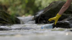 Plastic garbage in nature clean up waste water. Volunteer hands picks up a plastic bottles from mountain river. Environmental conservation volunteer cleaning up a forest river. Picking up trash water - Powered by Shutterstock - Get 15% off with code: PIKWIZARD15
