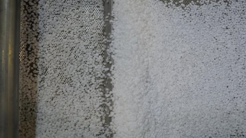 Recycled plastic granules - propylene or polyethylene pellets on shale shaker, conveyor belt of waste plastic recycling machine - top view. Separation, automated technology concept